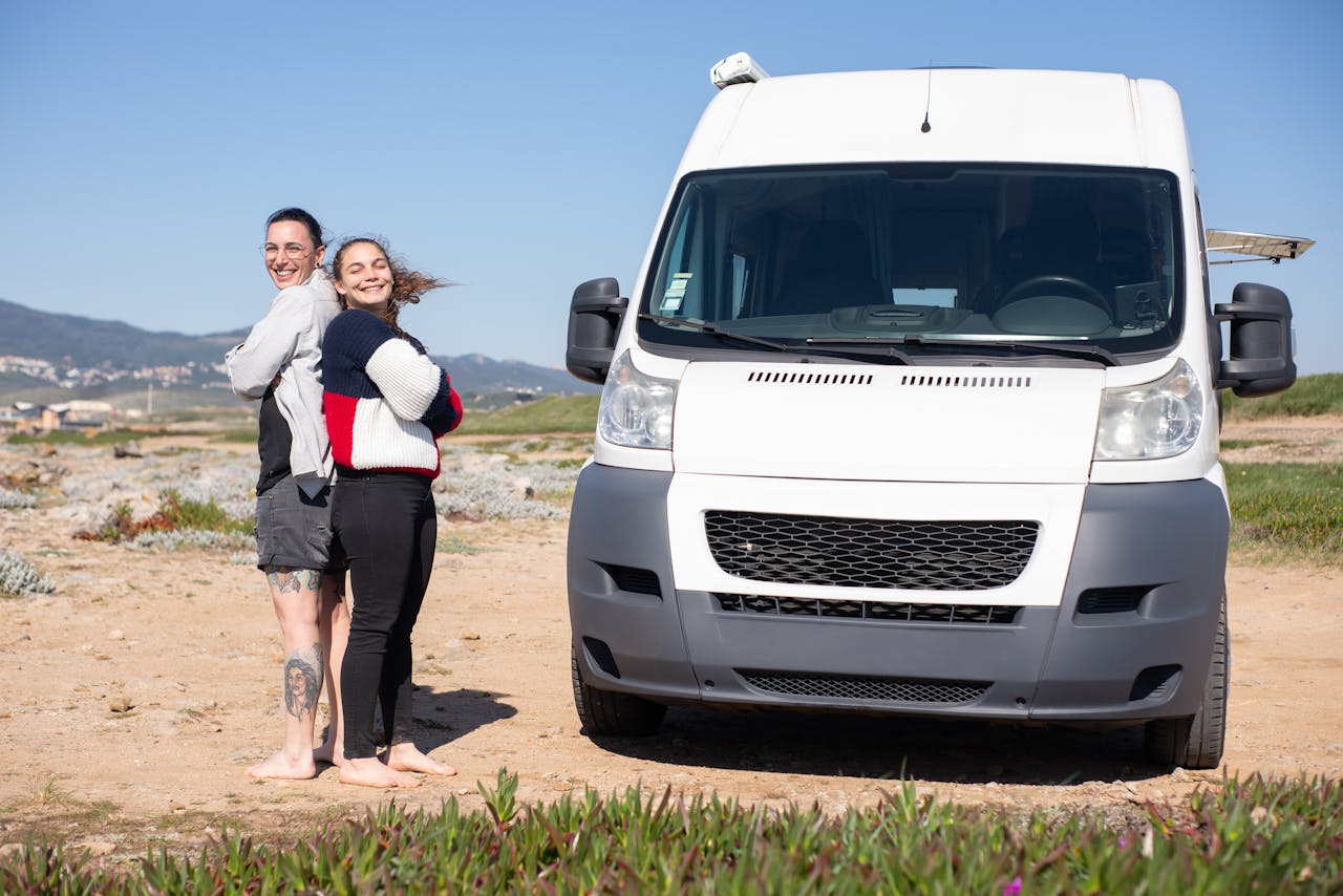 A joyful couple enjoying a sunny day with their camper van during a road trip in Portugal.