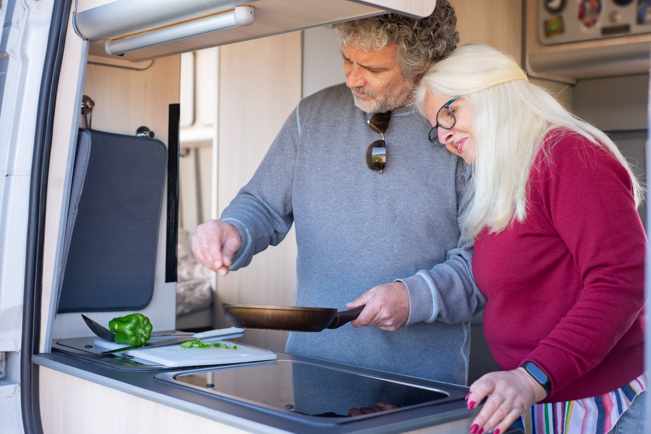 Senior couple cooking together in a motorhome kitchen during a travel trip in Portugal.